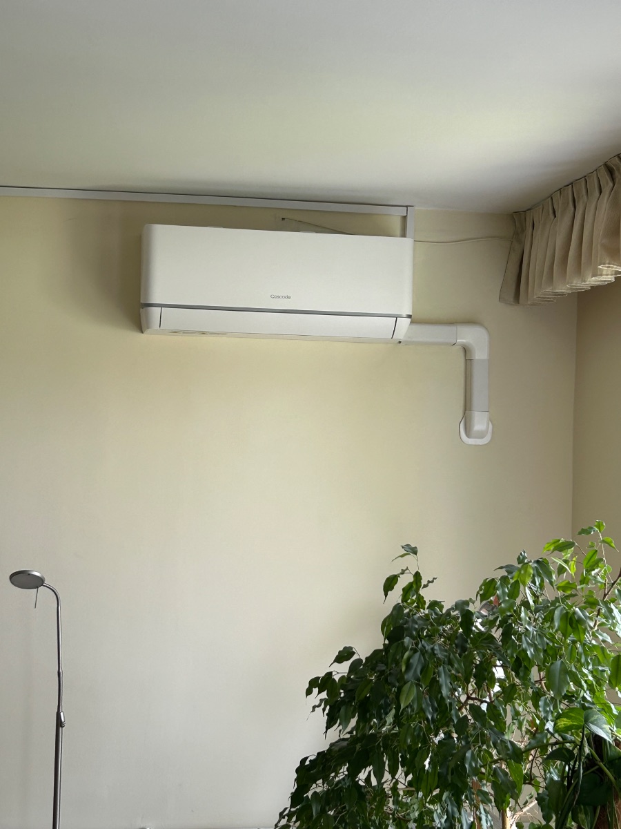 Split klíma beltéri egység nappaliban, esztétikus burkolt csővezetékkel